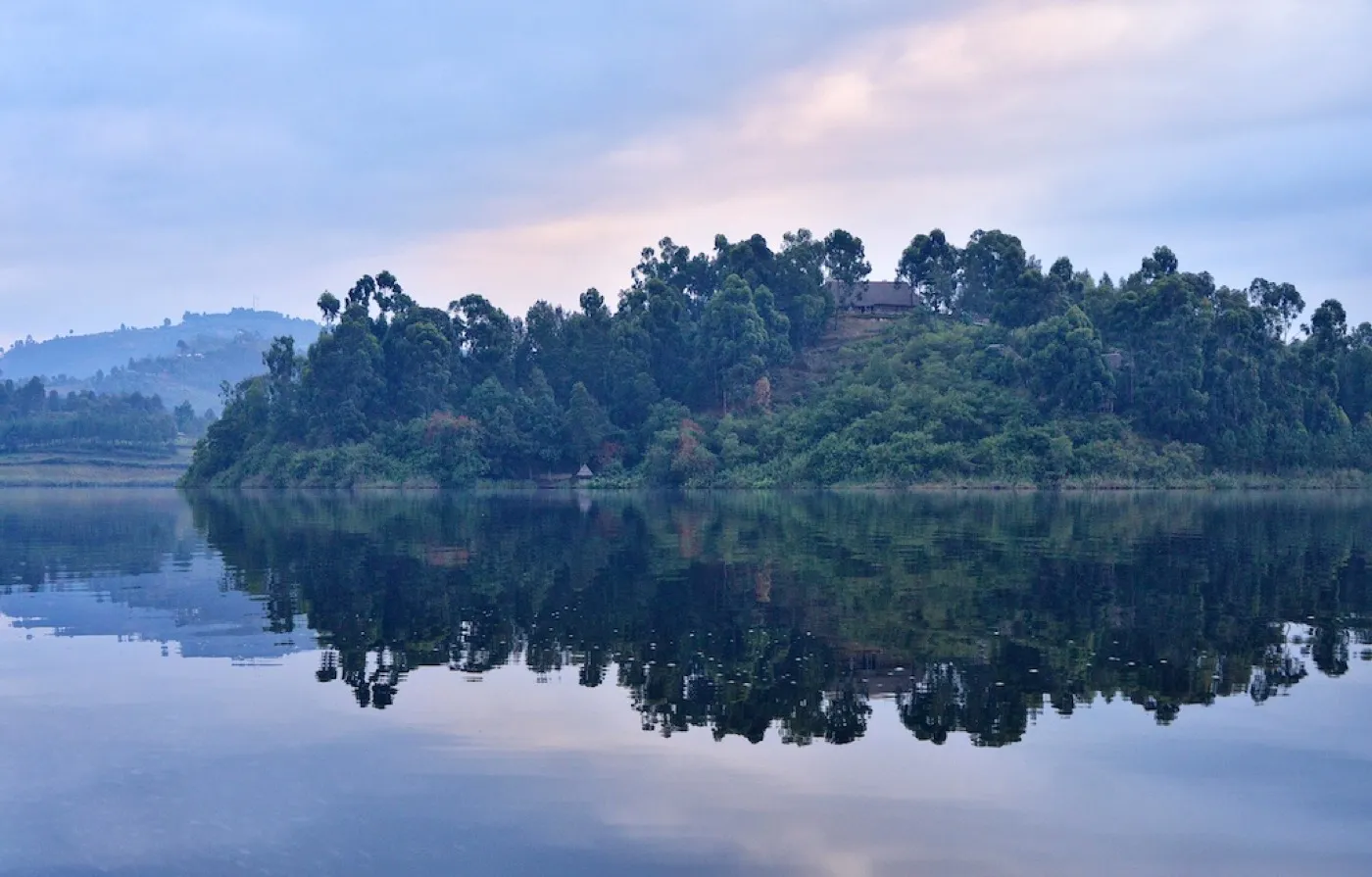 Lake Bunyonyi surrounded by steep green terraced hills at evening
